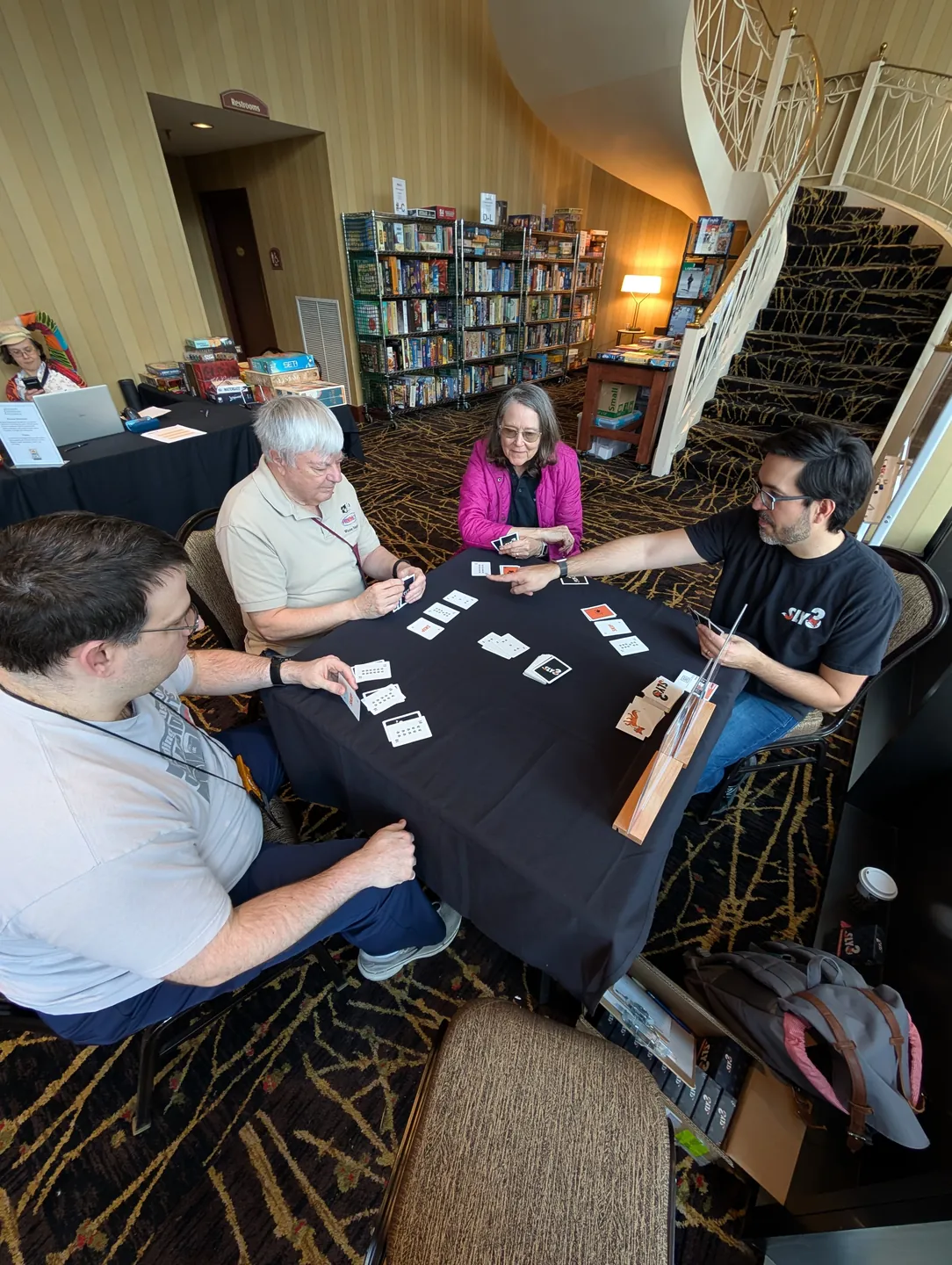 Four players focused on a Sly3 round at a convention table